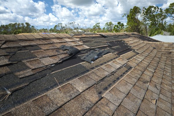 Damaged house roof with missing shingles after hurricane Ian in Florida. Consequences of natural disaster.